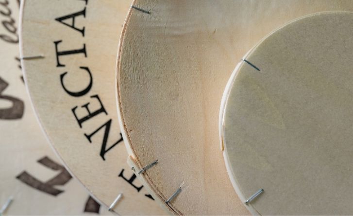 Zoom sur des boites en bois agrafées de différents volumes pour des fromages.